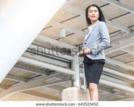 beautiful modern asian business woman tow luggage with modern city on background, business people concept.