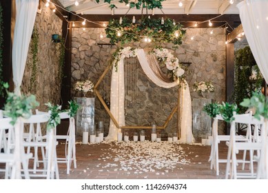 Beautiful Modern Hexagon Wedding Arch For Unique Contemporary Wedding Ceremony With Fresh Greenery And Lights And Candles.