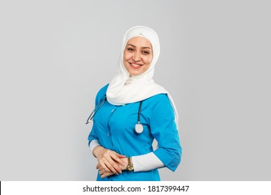 Beautiful Modern Muslim Doctor Or Nurse In Hijab On A Gray Background. Blue Uniform. Healthcare Concept
