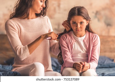 Beautiful Mom Is Combing Her Daughter's Hair, Girl Is Sitting Angrily