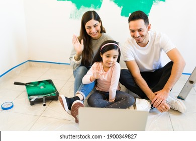 Beautiful Mom, Dad And Daughter Calling Their Friends And Familly To Show Them Their New Living Room. Parents And Little Girl Talking To Their Family By Video Call During Their Home Renovation