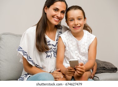 Beautiful Mom And Daughter At Home, Showing Something On The Phone