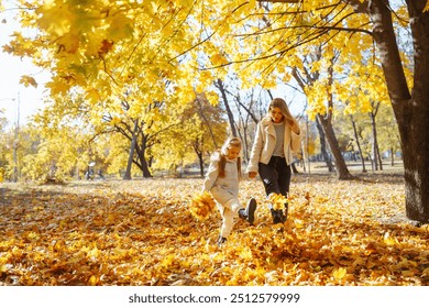 Beautiful Mom and daughter joyfully playing in vibrant autumn leaves at a sunny park on a clear day in October. Family day. - Powered by Shutterstock