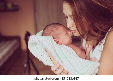 Beautiful Mom Kiss Baby To Noise. Mom With Newborn Baby In Hands Wrapped With Wool Blanket. True Mom Love To Her Baby. Care And Responsibility Towards The Child. Shelter Security In Mom's Embrace