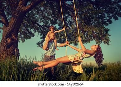 Beautiful mom on the swing in the forest with her family  - Powered by Shutterstock