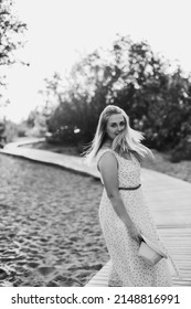 Beautiful Mom In The Park, In A Summer Dress. Loose Hair And Open Arms. Summer.