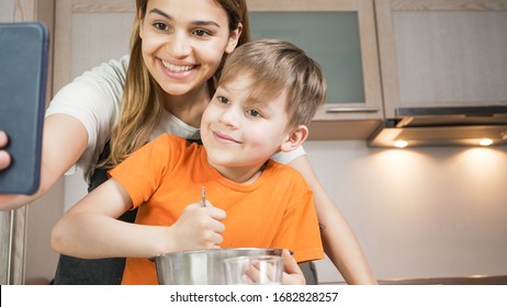 Beautiful Mom And Son Cooking And Making Selfie At Home. Happy Family Having A Facetime Video Call. Unity, Connection, Home Education Concept.