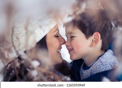 Beautiful Mom Tenderly Holding Her Adorable, Little Boy In Winter And Eskimo Kisses Him