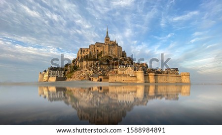 Beautiful Mont Saint Michel with water reflection and clouds on blue sky, France