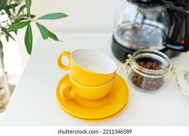 Beautiful Morning, The Process Of Making Coffee. Selective Focus, Noise. An Automatic Drip Coffee Maker Stands With A Yellow Cup On A White Table. Electric Kitchen Small Household Appliances