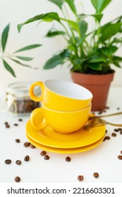 Beautiful Morning, The Process Of Making Coffee. An Automatic Drip Coffee Maker Stands With A Yellow Cup On A White Table, Scattered Coffee Beans. Green Flowerpot On The Background