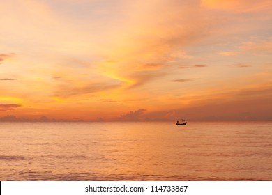 A beautiful morning sky with a fisherman on a boat in the sea, a beautiful orange sky with cloud reflection on the sea. Taken at Hua hin beach, Prachuabkhirikhan, Thailand. - Powered by Shutterstock