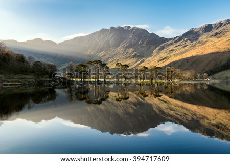 Beautiful morning sunlight shining on Buttermere in the Lake District with mirror like reflections. 