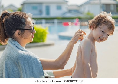 Beautiful mother applying roll on sunscreen to back of son to protect baby from sun at sunny poolside. Sunscreen for children. - Powered by Shutterstock