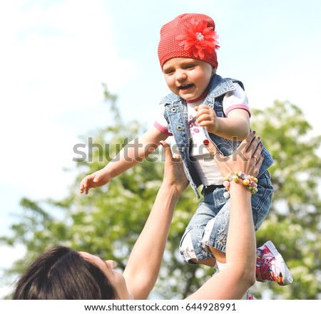 Beautiful Mother And Baby outdoors. Nature. Beauty Mum and her Child playing in Park together. Outdoor Portrait of happy family. Mom and Baby portrait