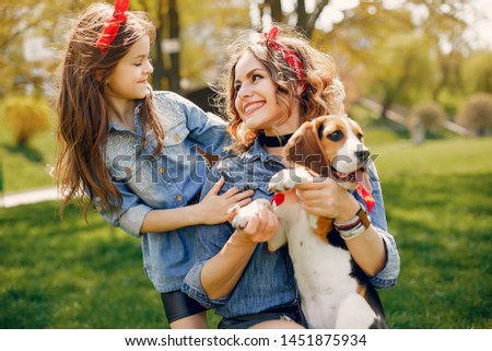 Beautiful mother with daughter. Family in a spring park. Woman in a blue shirt. Family with a cute dog