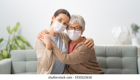 Beautiful mother and daughter are hugging while sitting on couch at home. - Powered by Shutterstock