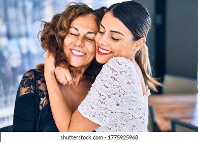 Beautiful mother and daughter smiling happy and confident. Standing with smile on face hugging at restaurant