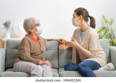 Beautiful mother and daughter are talking and smiling while sitting on couch at home. - Powered by Shutterstock