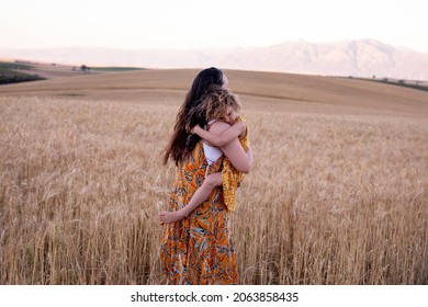 A beautiful mother and daughter in a wheat field. In the country. Laugher and fun. The mother is hugging her daughter.  - Shutterstock ID 2063858435