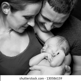 Beautiful Mother And Father Smiling Holding Their Newborn Baby Boy