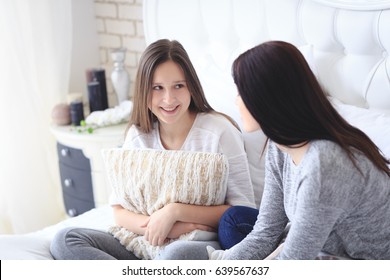 Beautiful Mother And Her Cute Teenage Daughter Talking Each Other, Sitting In Bedroom