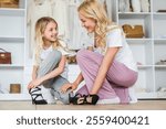 Beautiful mother and her little daughter have fun at home. Girl trying on her mother