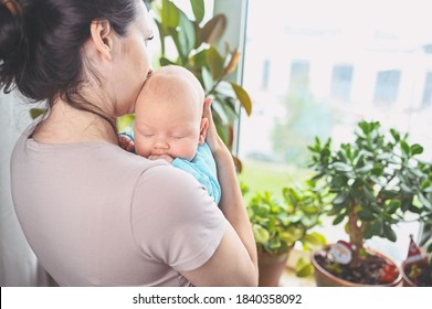 Beautiful Mother Holding In Arms Her Little Cute Newborn Infant Son. Baby Facial Expressions. Family At Home By The Window. Healthy Child, Concept Of Hospital And Happy Motherhood. Nursery.