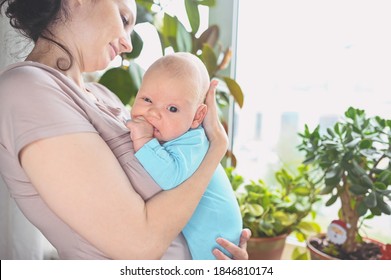 Beautiful Mother Holding In Arms Her Little Cute Newborn Infant Son. Baby Facial Expressions. Family At Home By The Window. Healthy Child, Concept Of Hospital And Happy Motherhood. Nursery.