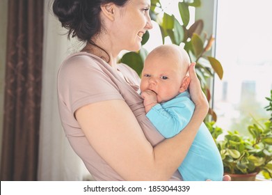 Beautiful Mother Holding In Arms Her Little Cute Newborn Infant Son. Baby Facial Expressions. Family At Home By The Window. Healthy Child, Concept Of Hospital And Happy Motherhood. Nursery.