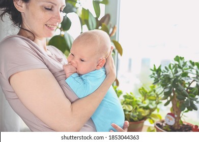 Beautiful Mother Holding In Arms Her Little Cute Newborn Infant Son. Baby Facial Expressions. Family At Home By The Window. Healthy Child, Concept Of Hospital And Happy Motherhood. Nursery.