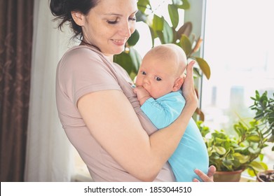 Beautiful Mother Holding In Arms Her Little Cute Newborn Infant Son. Baby Facial Expressions. Family At Home By The Window. Healthy Child, Concept Of Hospital And Happy Motherhood. Nursery.