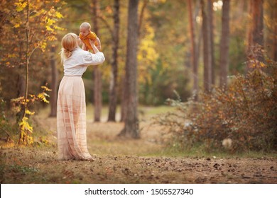 Beautiful Mother Holding Her Baby. Mom Loves Her Son. Family Time In Autumn Nature. Copy Space On Background