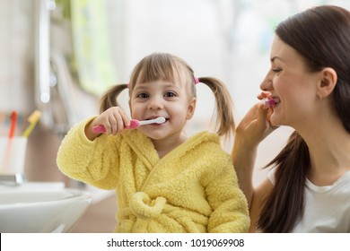 Beautiful Mother And Kid Daughter Brushing Teeth In Bathroom