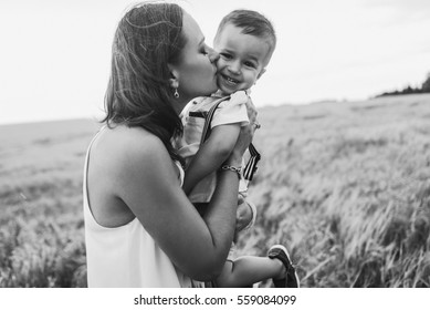 Beautiful Mother Young Son Walking In Wheat Field. Mother Tenderly Touches Her Son's Hair, Holding Hands, Hugs And Throws Up In The Sky. Mother's Love