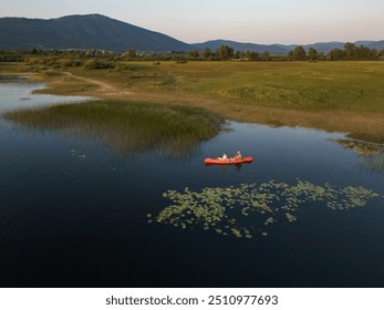 Beautiful mountain lake scenery with two people enjoying recreation paddling a red canoe, aerial shot. Summer vacation concept. - Powered by Shutterstock