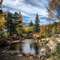 Beautiful Mountain Landscape With Changing Leaves In The Fall, Pond, And Pedestrian Bridge In Estes Park, Colorado