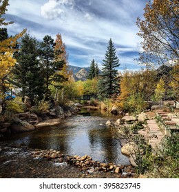 Beautiful Mountain Landscape With Changing Leaves In The Fall, Pond, And Pedestrian Bridge In Estes Park, Colorado