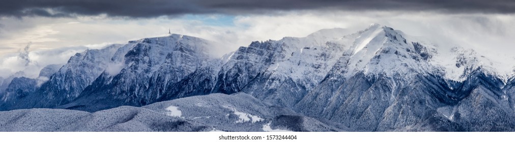 Beautiful mountain panorama in winter with fog and clouds. Bucegi mountains seen from Postavaru, Romania. 