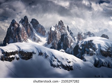 Beautiful mountain peaks in snow in winter. Dramatic landscape with high snowy rocks, overcast sky with clouds in cold evening. Tre Cime in Dolomites, Italy. Alpine mountains. Nature. Dark scenery - Shutterstock ID 2105297282