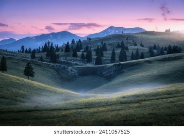Beautiful mountain valley with green hills in fog, pine trees, mountain peaks in haze, pink sky, sunlight at sunset in summer. Scenery. Alpine meadows at dusk in Velika Planina, Slovenia. Nature - Powered by Shutterstock