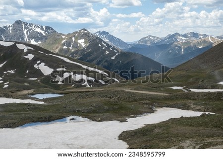 Beautiful mountain view with a clear, blue lake. Beautiful blue sky with clouds. Summer photo, but glaciers still have some snow left.