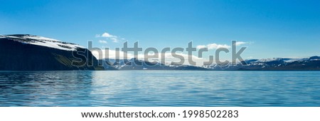 Beautiful mountains with snow picks and turquoise water of Atlantic ocean. Westfjords, Iceland. Horizontal banner with natural scenery.