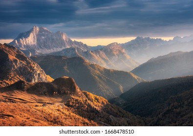 Beautiful mountains at sunset in autumn in Dolomites, Italy. Landscape with rocks, sunbeams, forest, hills with orange grass and trees, blue cloudy sky. Scenery with mountain valley in fog in fall - Powered by Shutterstock