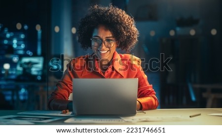 Beautiful Multiethnic Brazilian Female Working on Laptop Computer Late at Night. Young Creative Manager Having Fun in the Office, Chatting with Friends, Laughing and Feeling Happy.