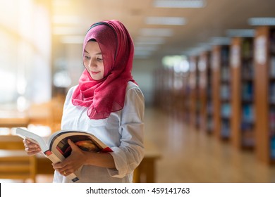 Beautiful Muslim girl reading book with hijab on blur library background. - Powered by Shutterstock