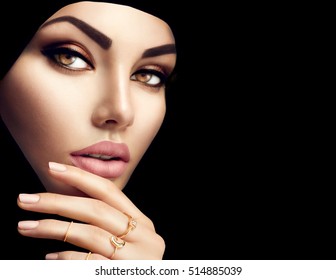Beautiful Muslim Woman face portrait. Hijab. Close up of beauty arabian woman with perfect makeup and manicure isolated on black background. Traditional muslim dress, hijab, burka, niqab