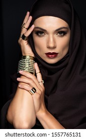 Beautiful Muslim Woman In Hijab With Makeup In Golden Rings And Bracelet Isolated On Black