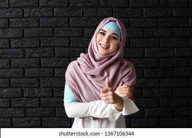 Beautiful Muslim woman showing thumb-up on dark background - Powered by Shutterstock