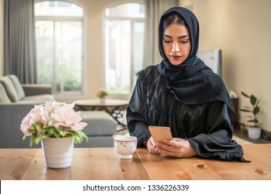 Beautiful muslim woman wearing abaya using smart phone while sitting at her luxury apartment. - Powered by Shutterstock